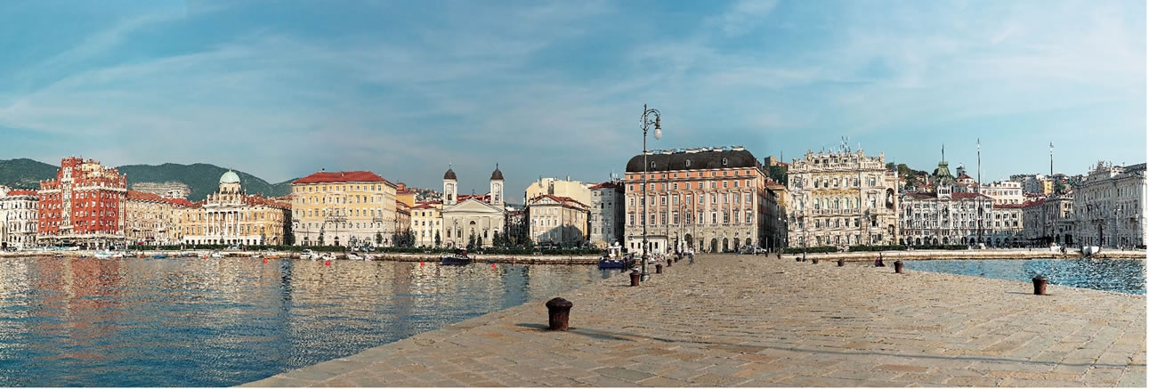 “le rive” dal molo audace e una panoramica di piazza Unità d’Italia, riordinata nella seconda metà dell’Ottocento. Su di essa insistono, da sinistra verso destra, il palazzo del Governo, costruito tra il 1901-’05 dal viennese E. Artmann; palazzo Stratti 